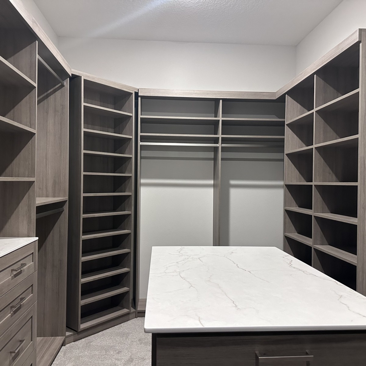 Luxury walk-in closet with gray wood grain cabinetry, quartz island, floor-to-ceiling shoe shelving, and hang sections, Florida