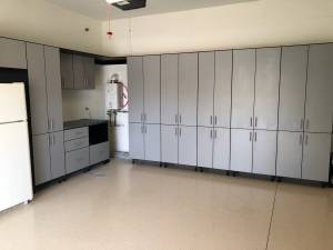 Custom garage cabinets with gray flat-front doors, black casework trim, and dark countertop, More Space Place Florida