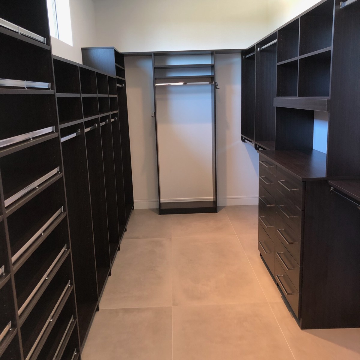 Custom dark espresso walk-in closet with flat drawer fronts, floor-to-ceiling shoe shelving, open hang sections, and clerestory window, More Space Place Florida