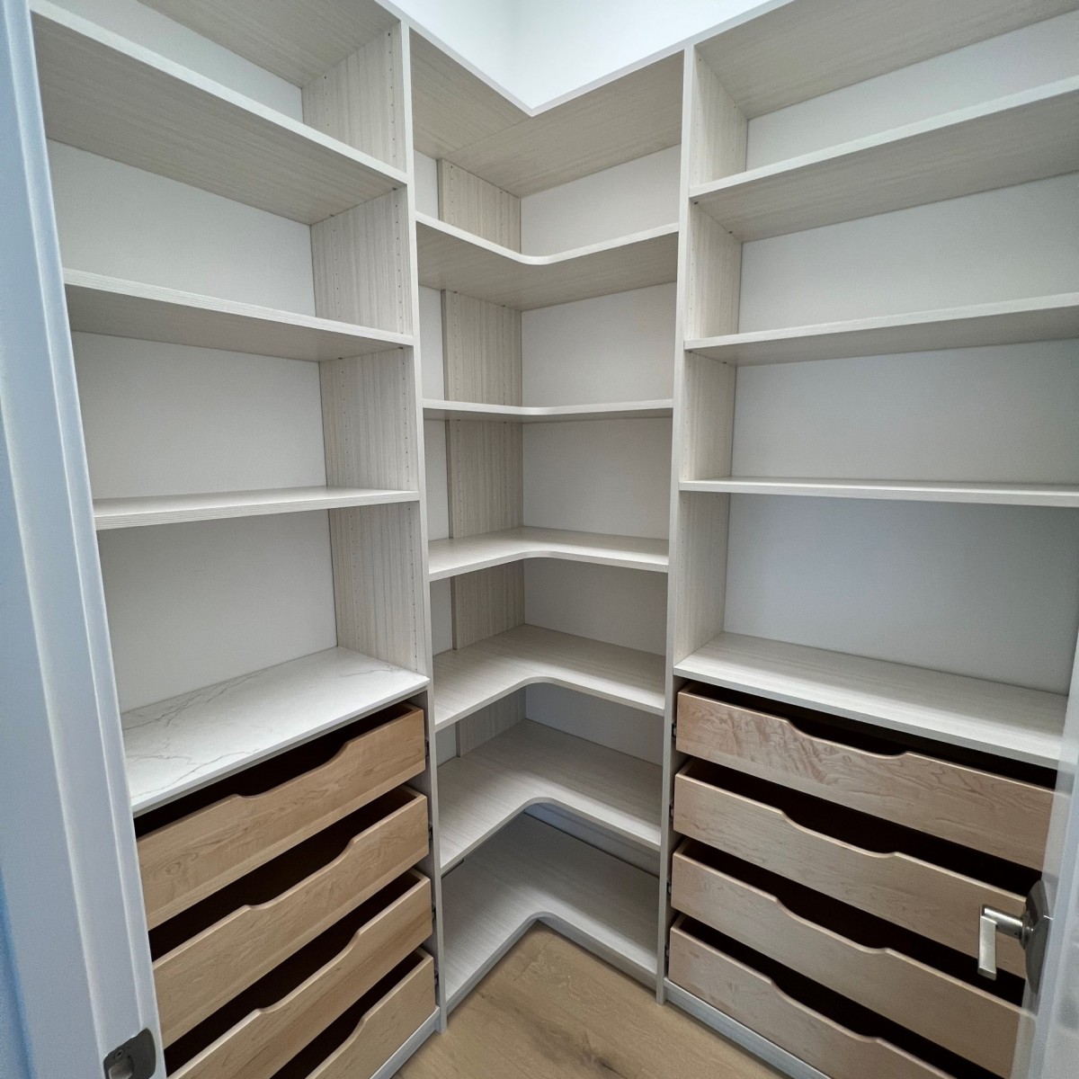 Walk-in pantry with white casework, adjustable shelving, and wood scoop front pull out drawers