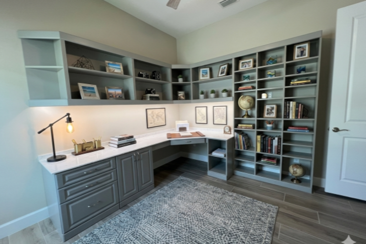 Custom home office built-ins in Celadon green traditional style with L-shaped Wilsonart Thinscape desk surface, raised-panel base cabinet doors, open upper shelving with LED underlighting, and floor-to-ceiling bookcase configuration